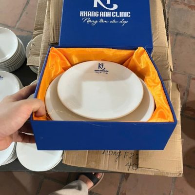 Hộp quà lót lụa màu vàng cam rực rỡ ôm trọn cặp đĩa sứ xếp chồng gọn gàng