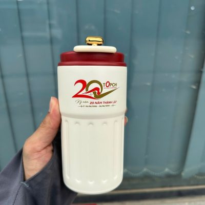 Cận cảnh ly giữ nhiệt màu kem trang nhã với logo kỷ niệm 20 năm thành lập in sắc nét trên thân ly