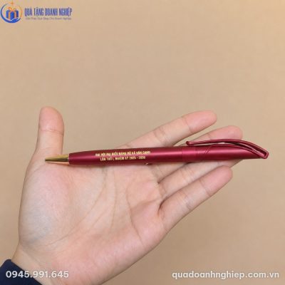 Bàn tay nâng niu chiếc bút bi BK-01 màu đỏ đô mờ có khắc chữ vàng sắc nét tôn vinh đại hội