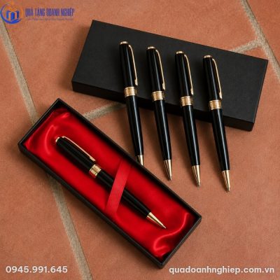Bộ bốn cây bút ký BK-0 màu đen mạ vàng xếp cạnh hộp đựng lót lụa đỏ trên nền gạch nung ấm áp