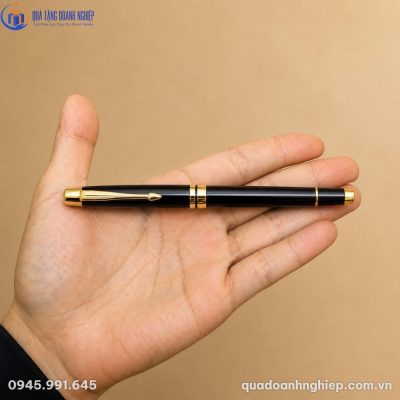 Cận cảnh bút ký kim loại BK-14 màu đen mạ vàng nằm gọn trong lòng bàn tay người dùng