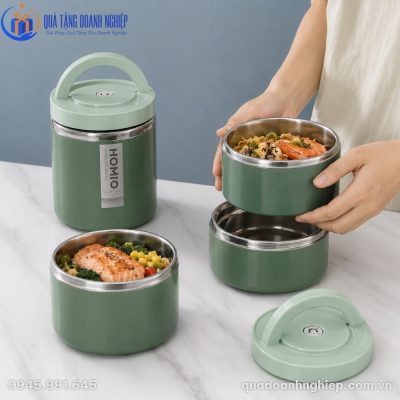 Các khay inox chứa cá hồi nướng và mì xào xếp chồng lên nhau vừa vặn trong lòng hộp