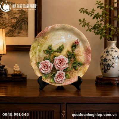 Đĩa biểu trưng hoa hồng đặt trang trọng trên bàn gỗ phòng khách bên cạnh bình hoa nghệ thuật