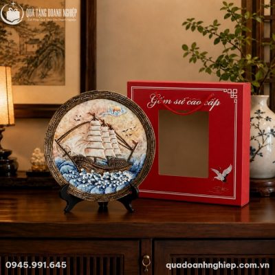 Cận cảnh họa tiết thuyền buồm đắp nổi tinh xảo trên đĩa sứ Bát Tràng đặt trên tủ gỗ trang trí