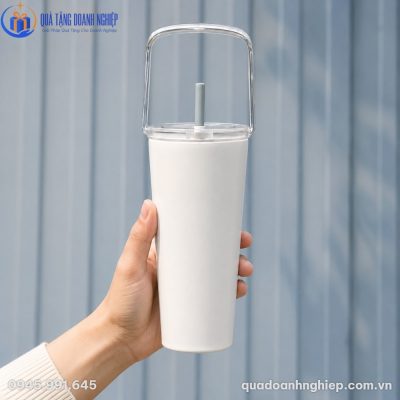 Cận cảnh chiếc ly giữ nhiệt màu trắng được cầm gọn trong lòng bàn tay, làm nổi bật quai xách trong suốt gập gọn phía trên