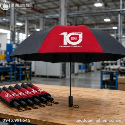 Bản thiết kế mô phỏng ô cầm tay ODQT-09 mở rộng đặt trên bàn gỗ nhà xưởng bên cạnh các bao đựng ô gấp gọn