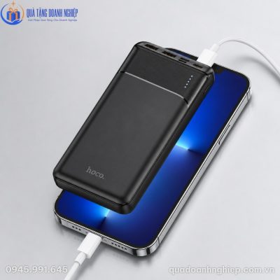 Thiết kế mỏng nhẹ của sạc dự phòng Hoco đặt phía trên điện thoại khi đang kết nối sạc cáp trắng