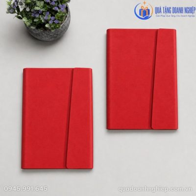 Hai cuốn sổ bìa da PU đỏ vát xéo đặt song song trên mặt phẳng xám nhạt hiện đại