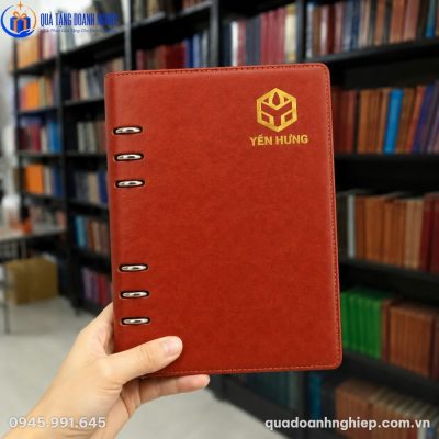 Cận cảnh cuốn sổ còng hở A5 màu nâu đỏ với logo Yến Hưng ép kim vàng nổi bật trên nền da PU