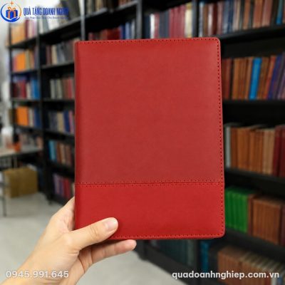 Cận cảnh cuốn sổ da SD-09 màu đỏ đô được cầm trên tay trong không gian thư viện