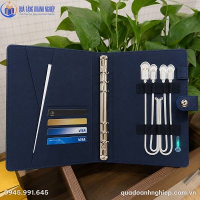 Sổ da sạc dự phòng đặt cạnh hộp xi lót định hình cao cấp màu đen ép kim logo đồng bộ trên mặt bàn gỗ