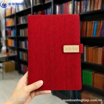 Cận cảnh cuốn sổ tay SD52 màu đỏ đô với các đường vân dọc sắc sảo được cầm trên tay trong không gian thư viện
