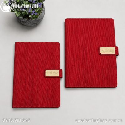 Hai cuốn sổ SD52 màu đỏ đô với kích thước cân đối đặt cạnh chậu cây trang trí nhỏ gọn