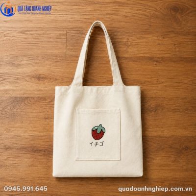 Túi canvas in hình quả dâu tây xinh xắn đặt phẳng trên mặt bàn gỗ tự nhiên