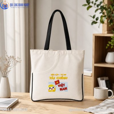 Thiết kế thực tế của túi canvas CVQT-07 với ngăn phụ bán nguyệt và hình in sắc nét đặt trên bàn gỗ