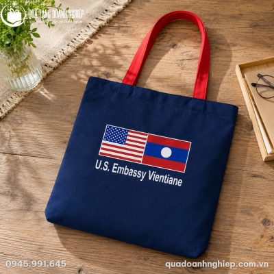 Mẫu túi vải canvas CVQT-03 phối màu xanh navy và quai đỏ nổi bật trên nền gỗ