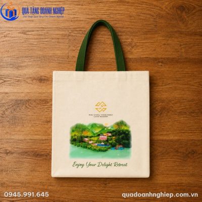 Thiết kế túi canvas phẳng phiu đặt trên mặt sàn gỗ tự nhiên làm nổi bật quai xách màu xanh lá dệt cotton dày dặn