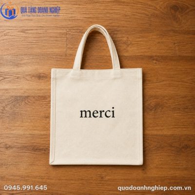 Túi vải canvas Merci thô mộc đặt phẳng trên nền sàn gỗ tự nhiên ấm áp