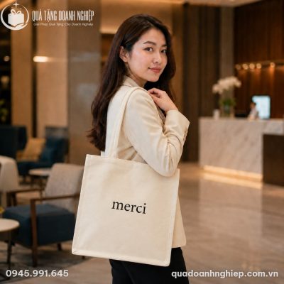 Thiếu nữ Việt Nam thanh lịch khoác trên vai chiếc túi canvas Merci trong không gian sảnh khách sạn hiện đại