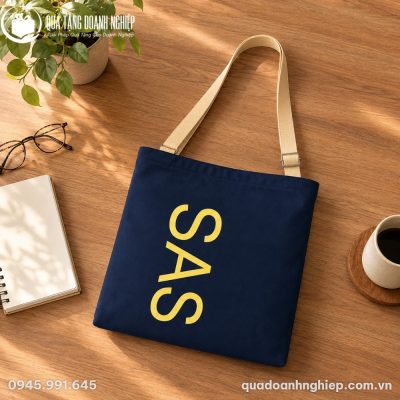 Cận cảnh túi canvas CV-05 đặt trên mặt bàn gỗ bên cạnh sổ tay và tách cà phê ấm áp
