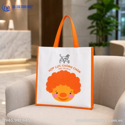 Cận cảnh túi vải không dệt phối cam đặt trên ghế sofa sang trọng tại sảnh chờ doanh nghiệp