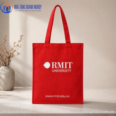 Cận cảnh túi vải canvas đỏ RMIT đặt trên mặt bàn đá với đường may quai xách gia cố chắc chắn