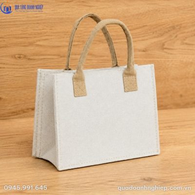 Cận cảnh túi canvas tự đứng dáng cứng cáp đặt trên mặt bàn gỗ tự nhiên ấm áp.